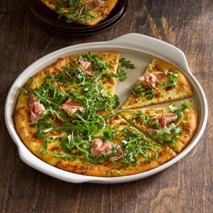 Großer runder Stein „White Lady“ von Pampered Chef® mit Pizza, Rucola und Schinken